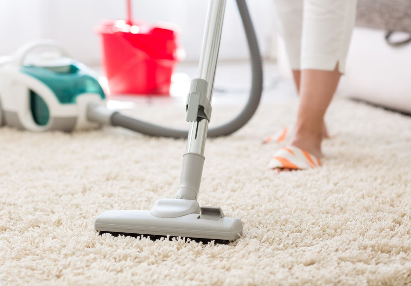 Vacuuming a living room carpet during a regular house clean